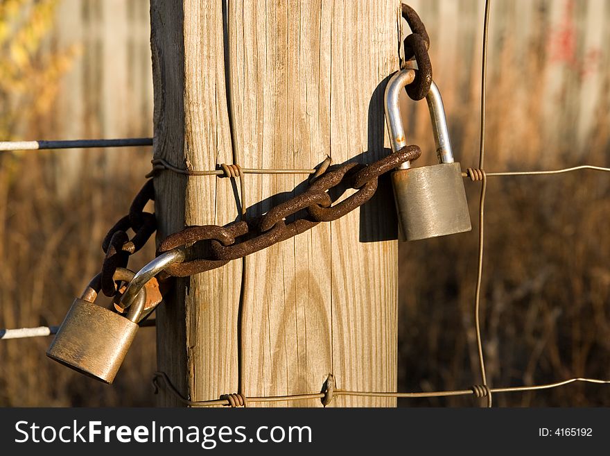 Old rusty locks and a chain on a wire and post fence. Old rusty locks and a chain on a wire and post fence