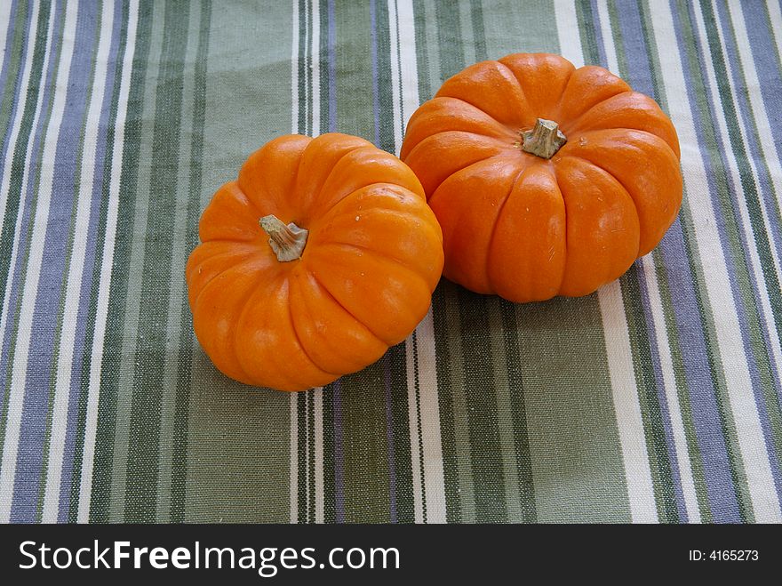 Small orange pumpkins on decorative cloth background.