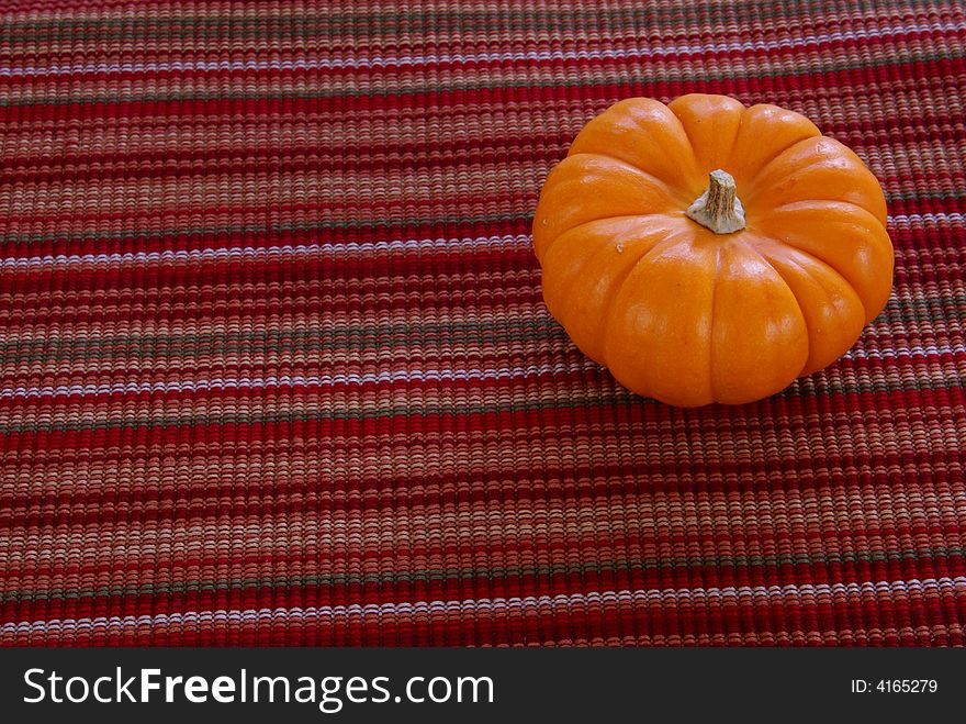 Small orange pumpkins on decorative cloth background.