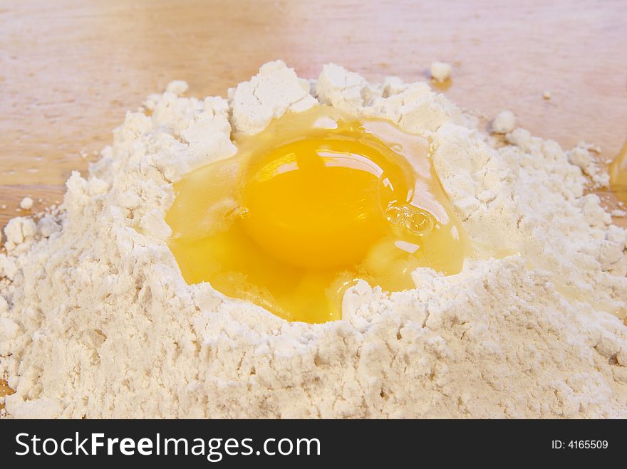 Raw egg in flour on wooden board