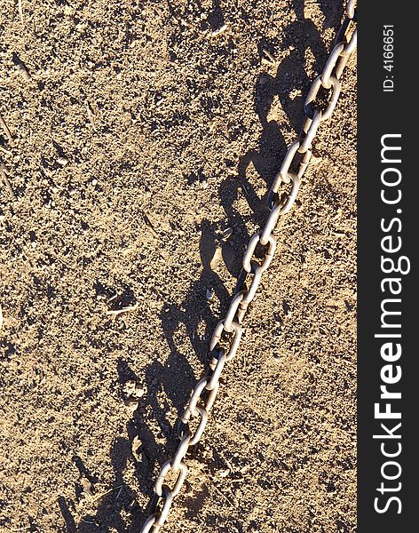 Metal chain and shadow in dirt, background or texture design element. Metal chain and shadow in dirt, background or texture design element