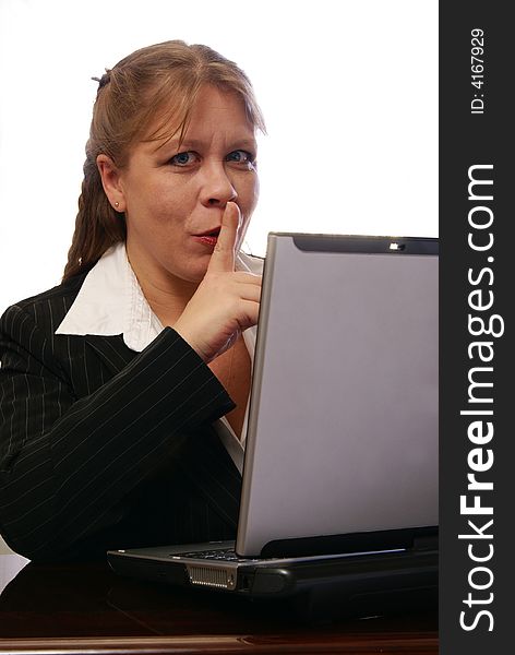 Friendly business woman holding finger up in be quiet gesture while working on laptop computer. Friendly business woman holding finger up in be quiet gesture while working on laptop computer