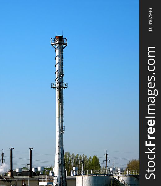 The factory chimney photographed on a background of the blue sky