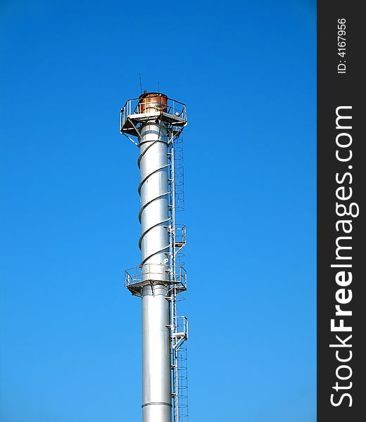 The factory chimney photographed on a background of the blue sky