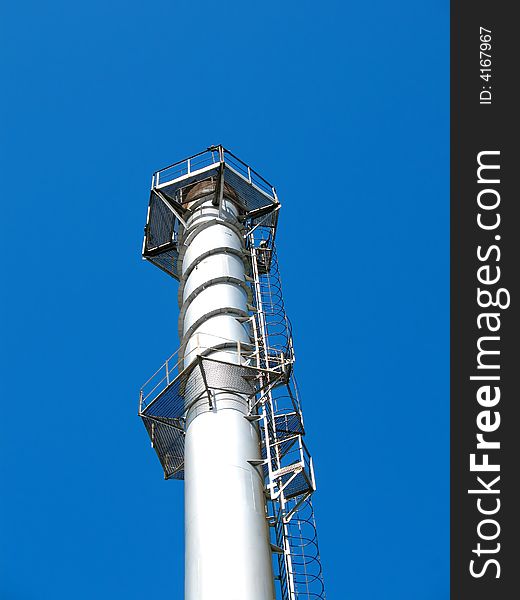 The factory chimney photographed on a background of the blue sky