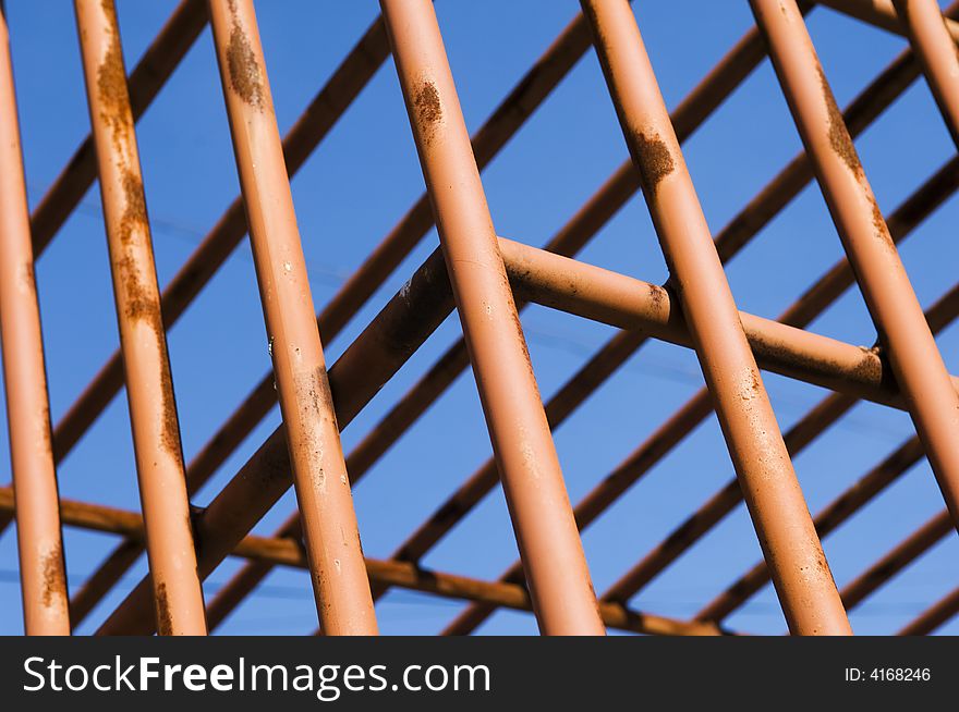 Rusty cage detail painted in red against the sky. Rusty cage detail painted in red against the sky