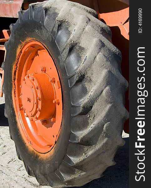 Close up of an orange tractor wheel on sand