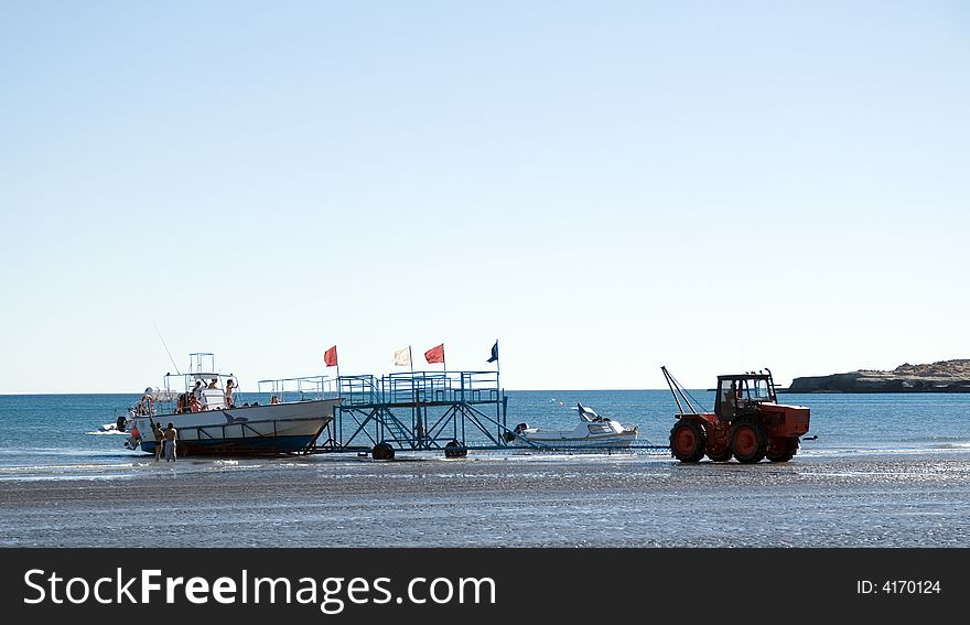 Boat full of tourists being pulled out of the water by a tractor at a beach in Patagonia, Argentina. Boat full of tourists being pulled out of the water by a tractor at a beach in Patagonia, Argentina.