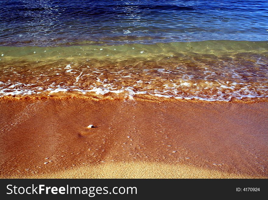 A small pebble getting bathed in the ocean waves. A small pebble getting bathed in the ocean waves.