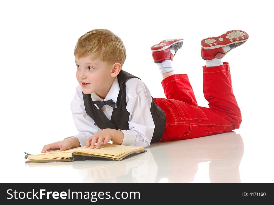 Young boy in smart clothes lying on ground reading book, white studio background. Young boy in smart clothes lying on ground reading book, white studio background.