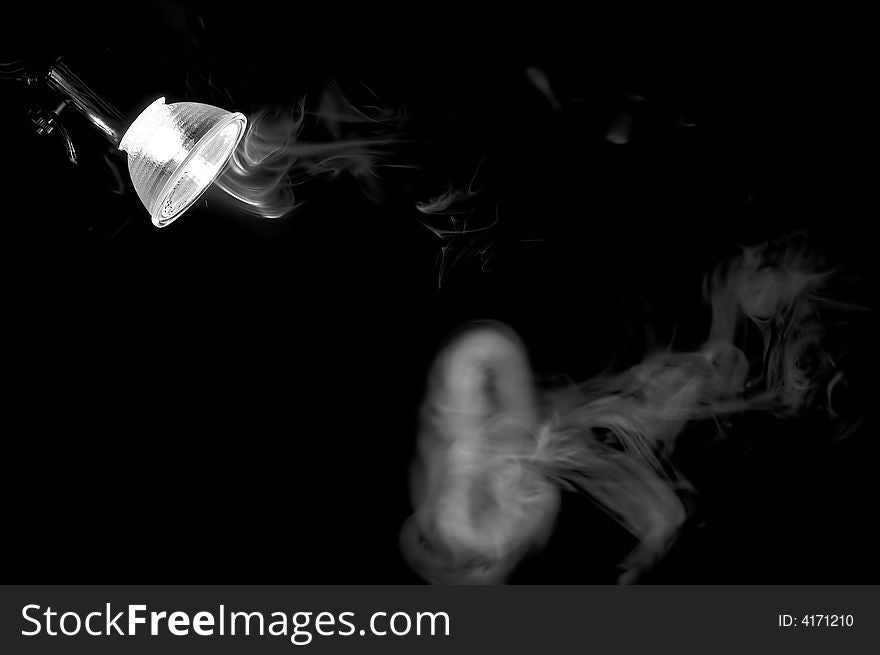 The smoke from a cigarette flies under a lamp. The smoke from a cigarette flies under a lamp