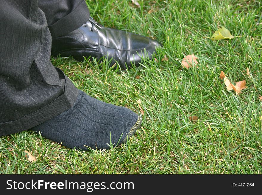 Business feet in grass without one shoe on. Business feet in grass without one shoe on