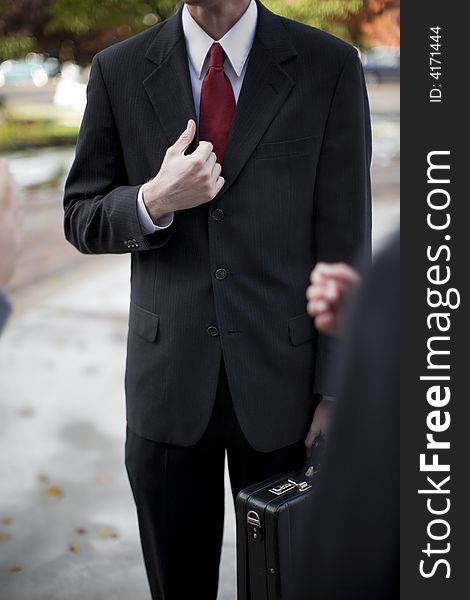 Over shoulder view of businessman in suit standing holding briefcase and part of his jacket