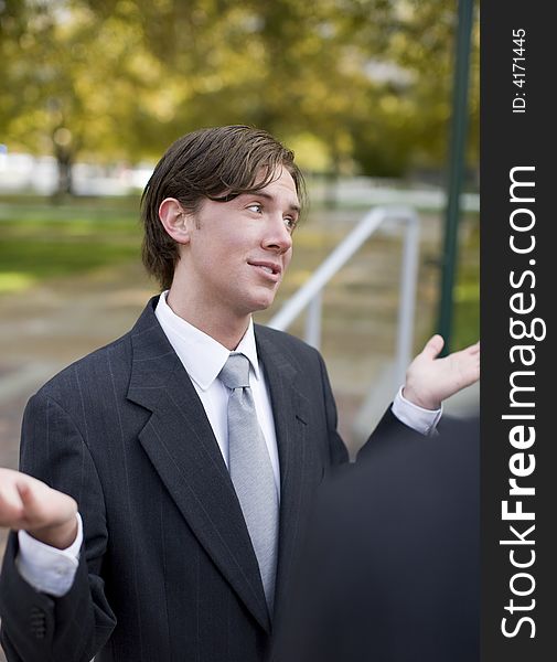 Over shoulder view of businessman standing in suit and tie with both hands up in air. Over shoulder view of businessman standing in suit and tie with both hands up in air