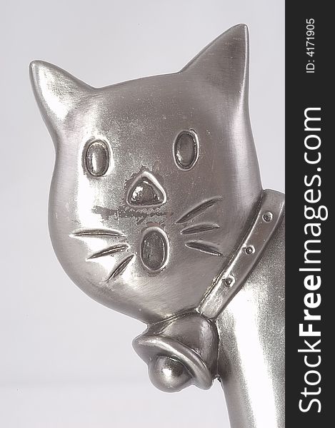 Head of a metal toy cat isolated on grey-white. Close-up.