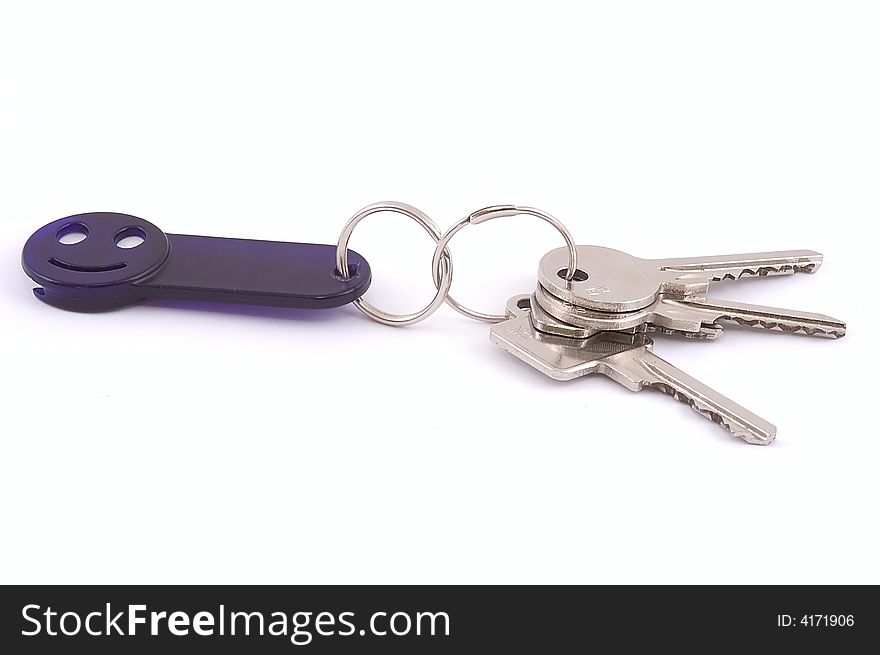 Bunch of keys with dark blue smile trinket isolated on white. Close-up. Bunch of keys with dark blue smile trinket isolated on white. Close-up.