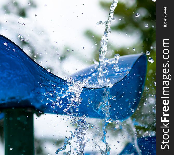 Water stream disrupted and broken up at the edge of a blue undulating plastic edge