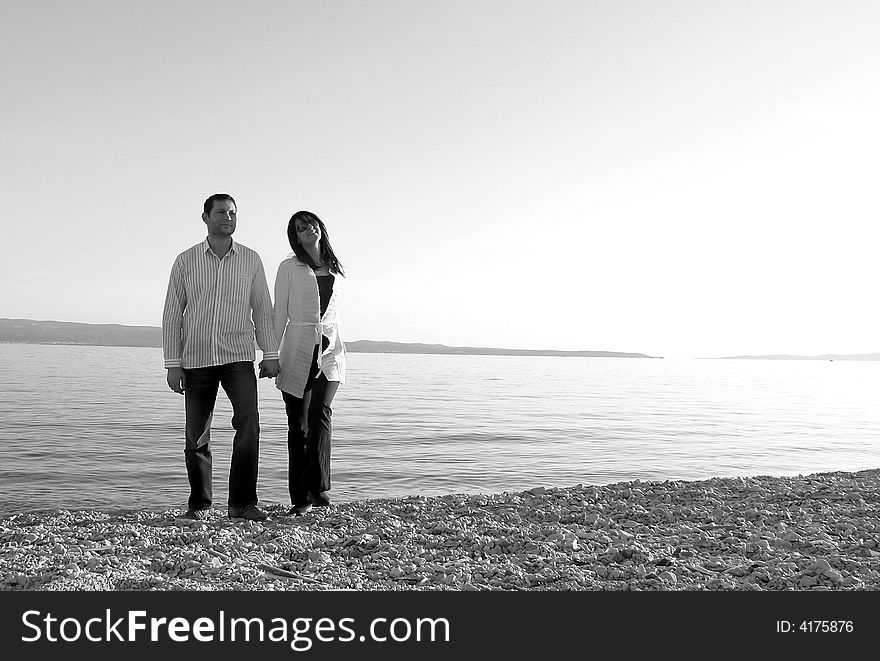 An attractive young couple walking along a beach. An attractive young couple walking along a beach.