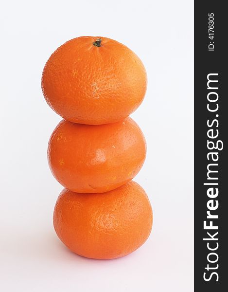 Pile of three orange tangerines isolated on white, vertical.