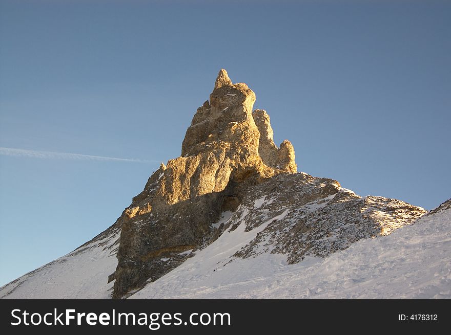 Cliff in snowy mountains in clear sky, horizontal.