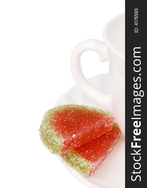 White tea cup and piece of fruit candy. White tea cup and piece of fruit candy