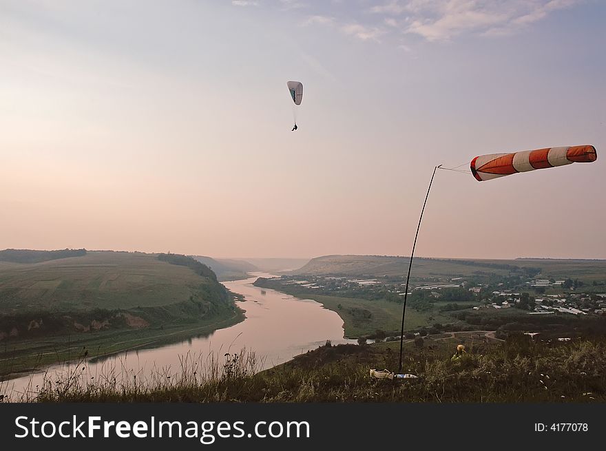 Man Flying on Paraglider in evening above the Dnestr river canyon, Ukraine