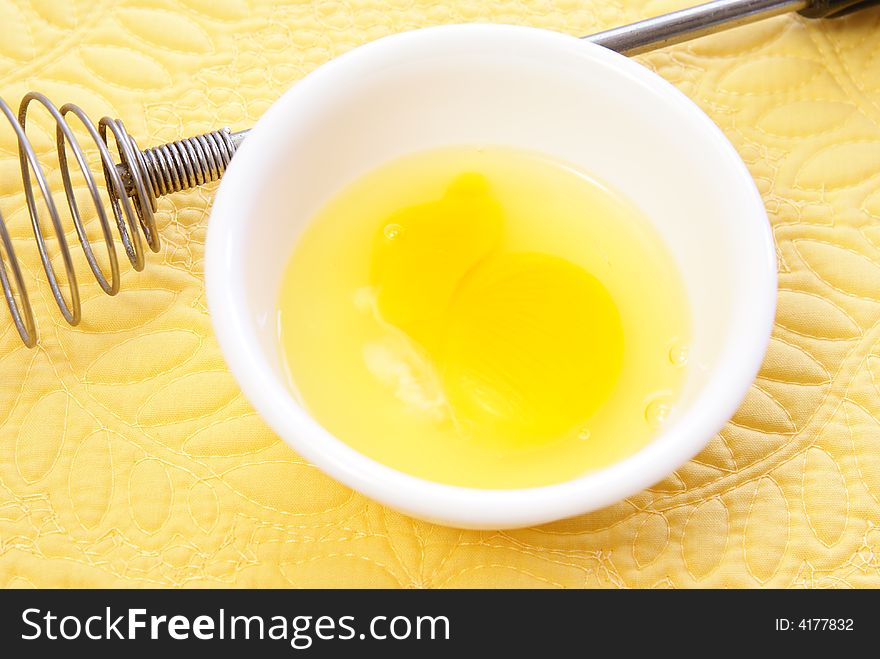 Raw egg in bowl on yellow placemat. Raw egg in bowl on yellow placemat