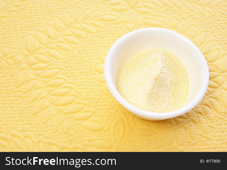 Ground cornmeal in white bowl on yellow placemat