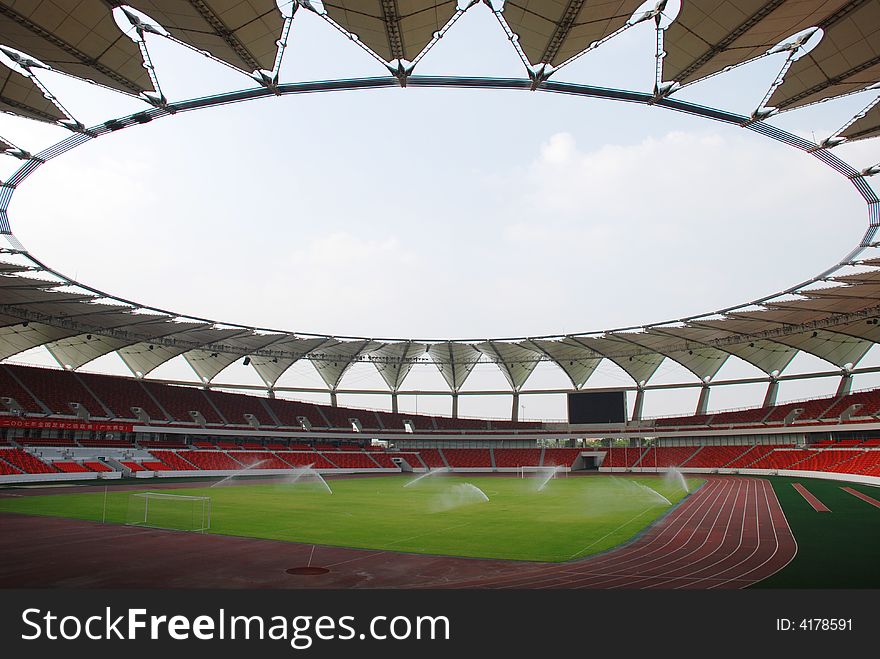 A large modern stadium with football pitch and circle dome