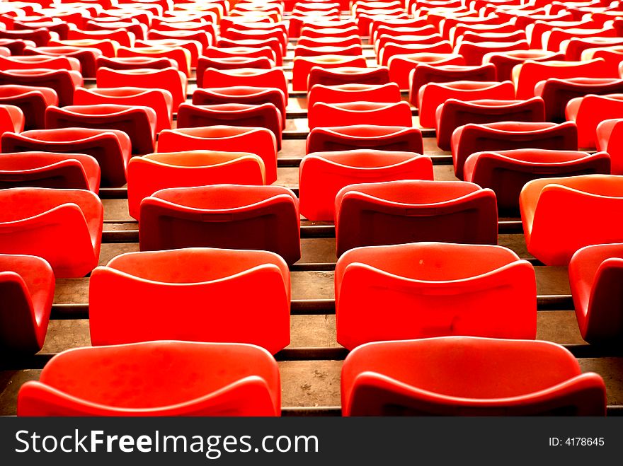Red plastic chairs in a stadium  form curves ,waves and parallele lines concentrating. Red plastic chairs in a stadium  form curves ,waves and parallele lines concentrating.