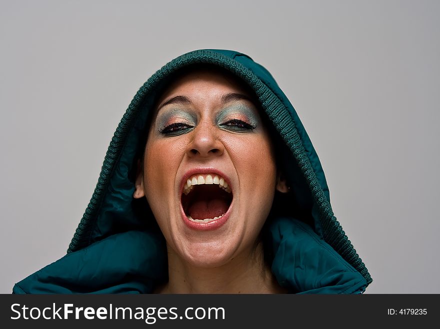 A beautiful young woman screaming aggressively wearing a green winter coat and the hood over her head, isolated on white. A beautiful young woman screaming aggressively wearing a green winter coat and the hood over her head, isolated on white