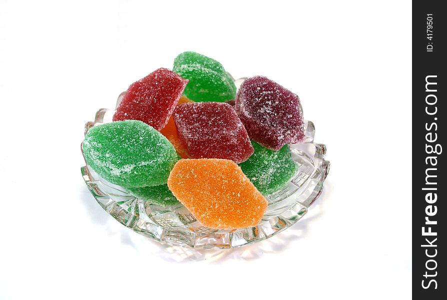 Fruit candies of different colors on crystal cut plate