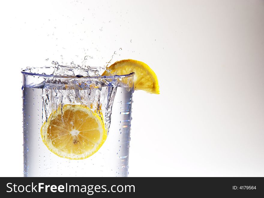 A lemon dropping into a glass of water. A lemon dropping into a glass of water.