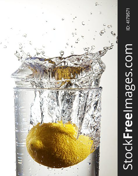 A lemon dropping into a  glass of water. A lemon dropping into a  glass of water.