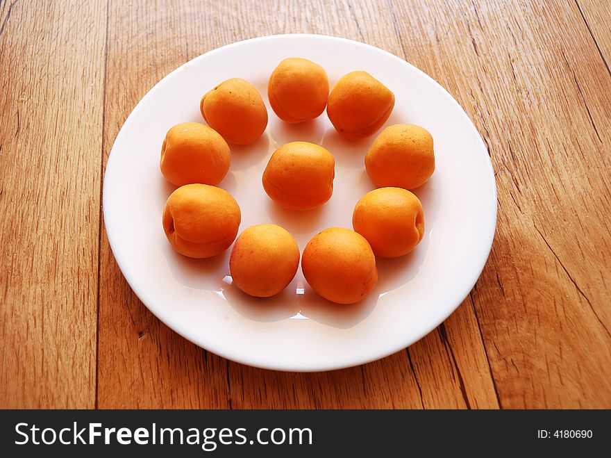 Apricots on the white plate, standing on the wooden table. Apricots on the white plate, standing on the wooden table