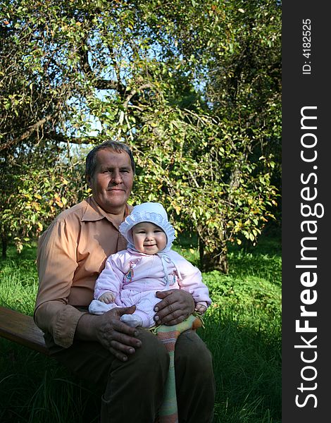 Grandfather and granddaughter sitting in the garden