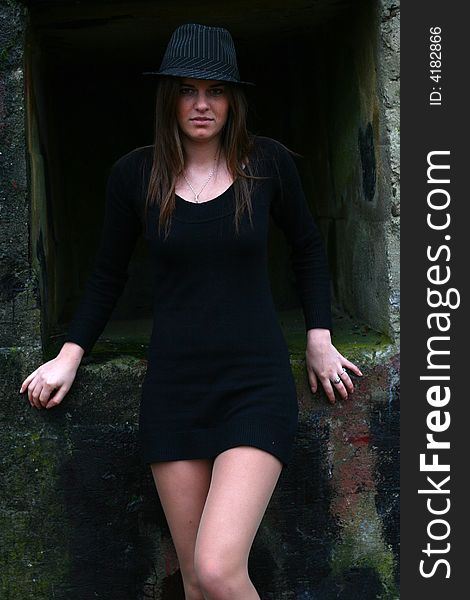 Young girl in the field on the warm winter day wearing black hat standing by the old military training path. Young girl in the field on the warm winter day wearing black hat standing by the old military training path