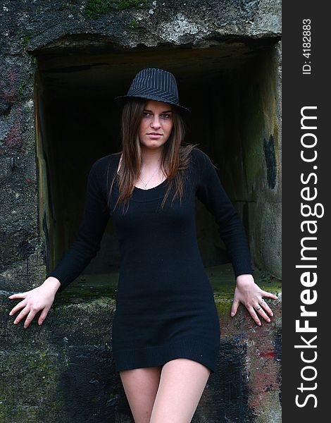 Young girl in the field on the warm winter day wearing black hat standing by the old military training path. Young girl in the field on the warm winter day wearing black hat standing by the old military training path