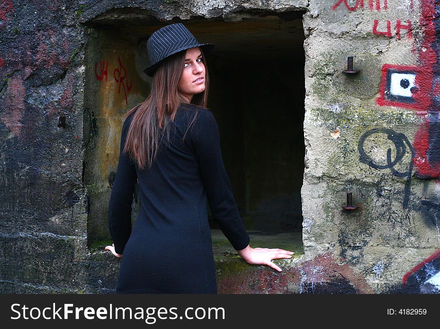 Young girl in the field on the warm winter day wearing black hat standing by the old military training path. Young girl in the field on the warm winter day wearing black hat standing by the old military training path