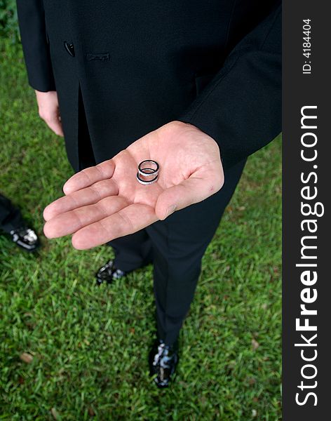 Close up view of a groom holding wedding rings in hand