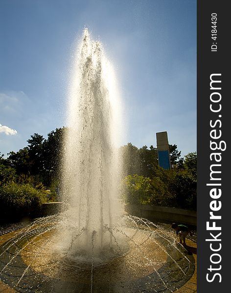 Backlit Water Fountain Against Blue Sky