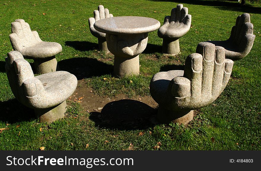 Concrete decorative a table and chairs in the form of a human hand on a green grass. Austria, Northern Tirol. Concrete decorative a table and chairs in the form of a human hand on a green grass. Austria, Northern Tirol.