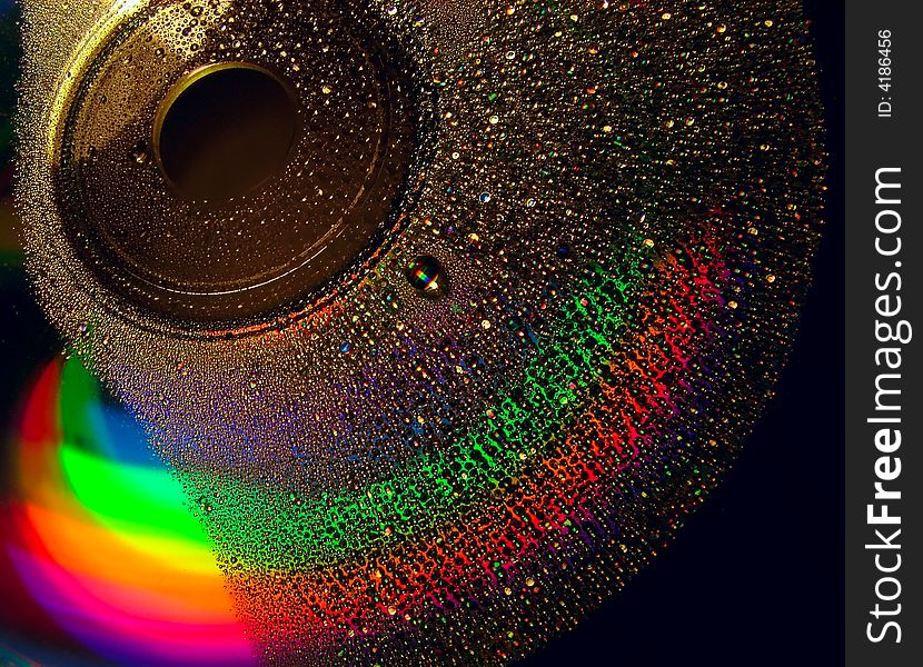 Full light spectrum on a cd quarter covered with water drops, black background. Full light spectrum on a cd quarter covered with water drops, black background