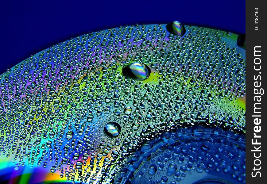 Full light spectrum on a cd quarter covered with water drops, blue background. Full light spectrum on a cd quarter covered with water drops, blue background