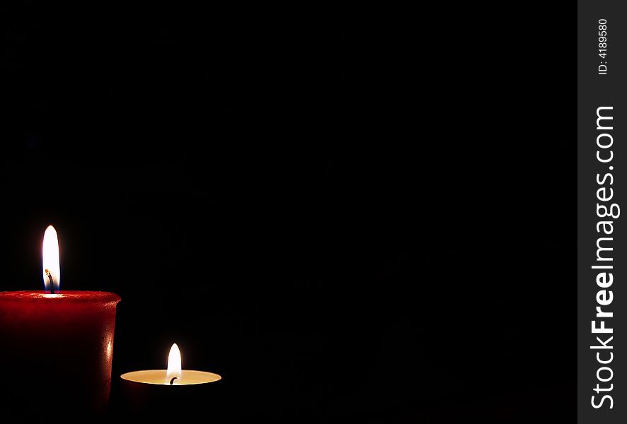 A red a white candle with a black background. A red a white candle with a black background.