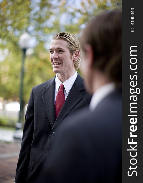 Over shoulder view of businessman standing in suit and tie talking. Over shoulder view of businessman standing in suit and tie talking