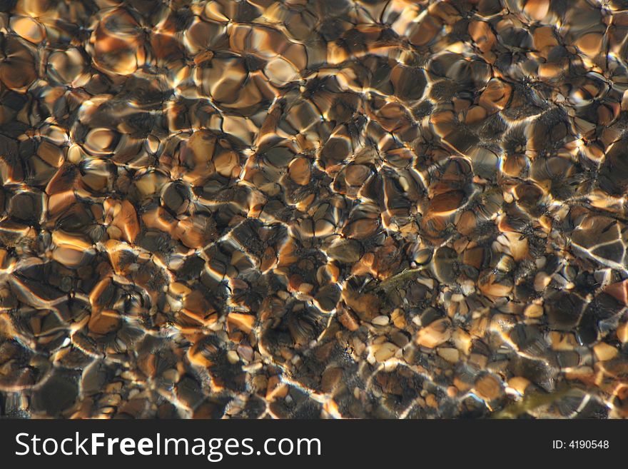 Looking down into a slow moving stream, with the sunlight playing across the rocks. Looking down into a slow moving stream, with the sunlight playing across the rocks.