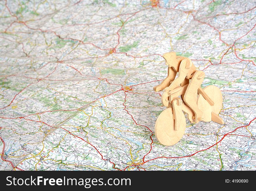 Wooden model of bicyclist on background of map. Wooden model of bicyclist on background of map