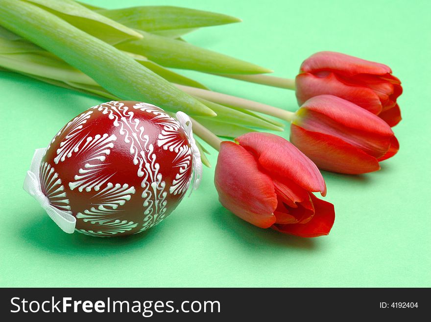 Painted Easter Egg and red tulips on a green
