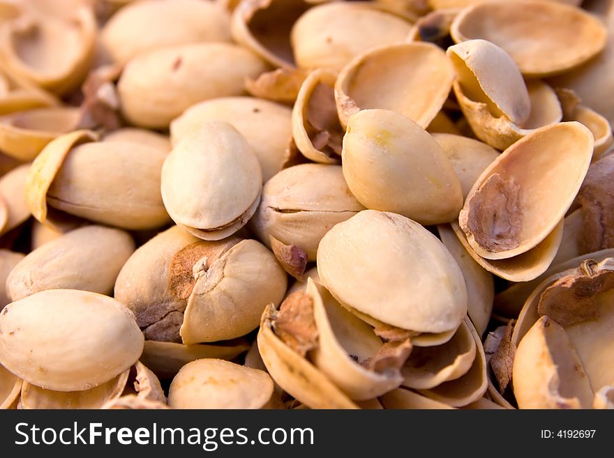 A collection of empty (eaten) pistachio shells in a pile.